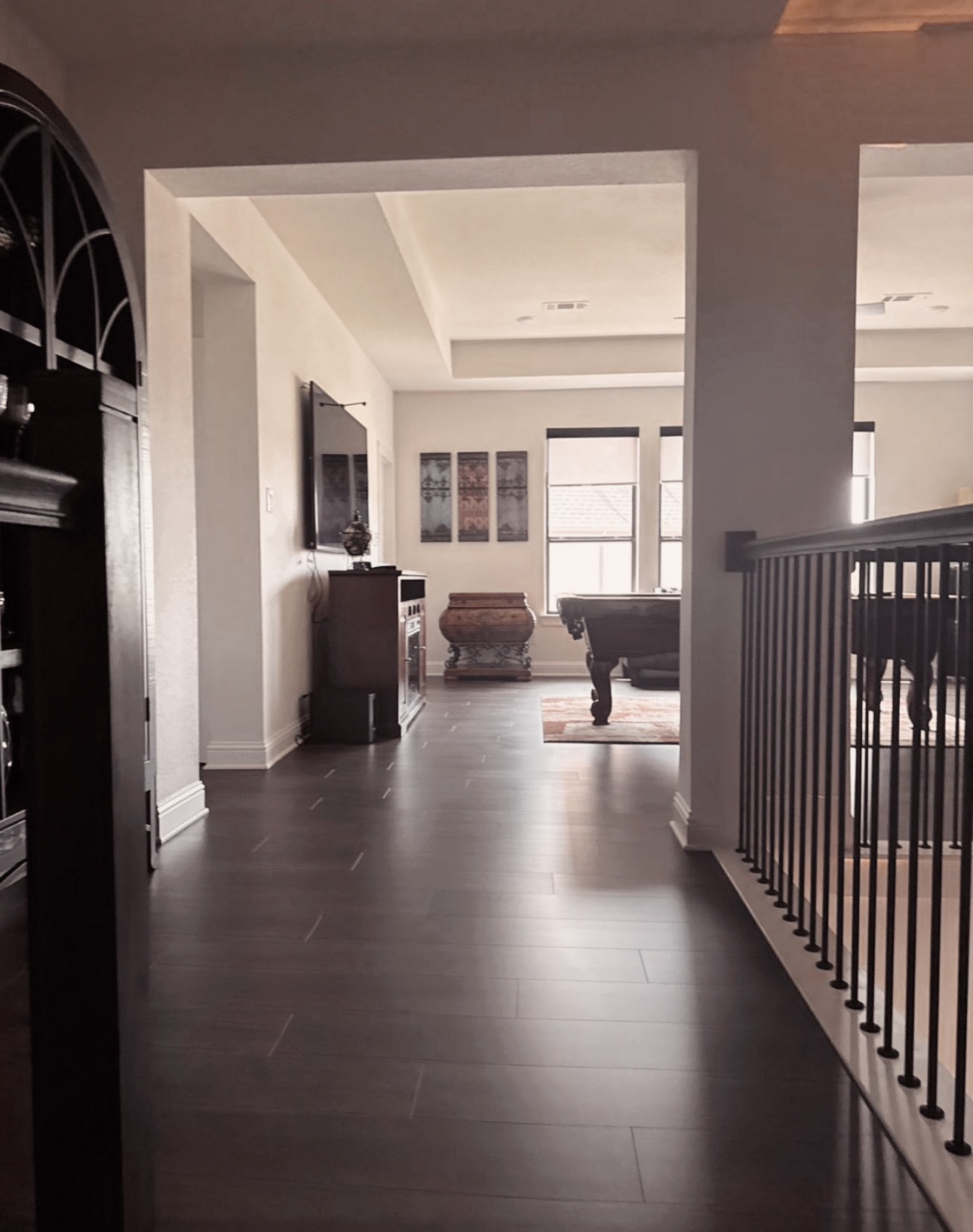 Clean hallway and game room with dark hardwood floors